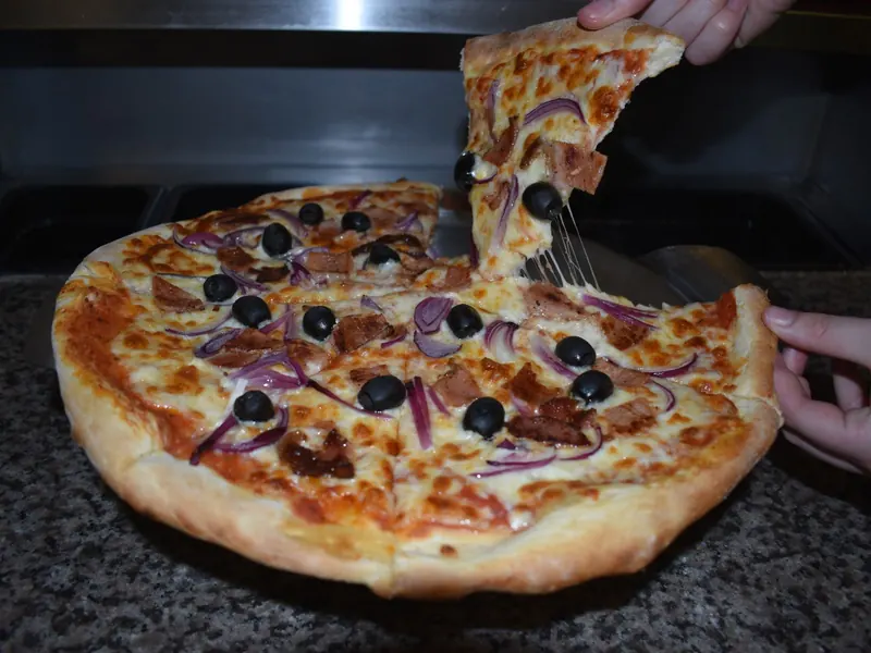 A fresh pizza with a slice being lifted