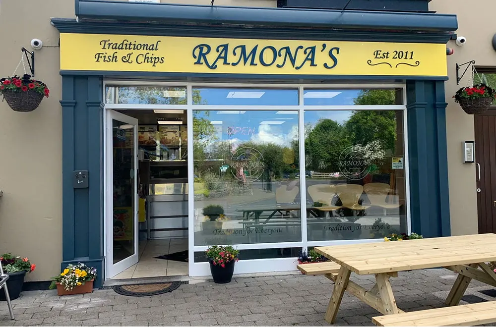 Ramona's shopfront on Station Road, Adare, with the yellow Est 2011 sign and picnic benches outside